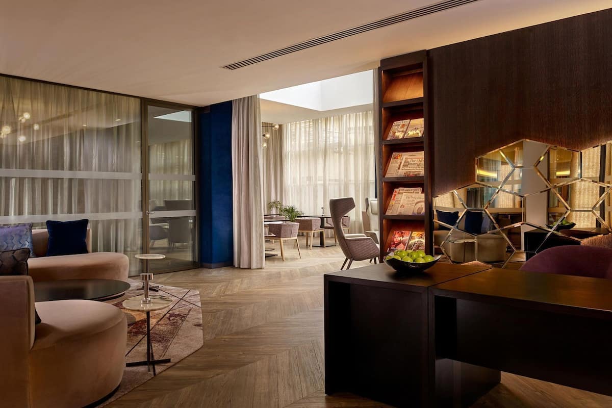 A modern living room with a large window, a bookshelf, and a dining area.