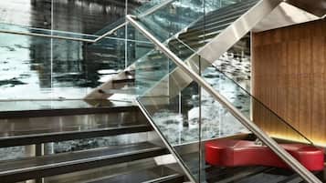 A modern staircase with glass railings and a wooden wall.