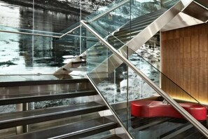 A modern staircase with glass railings and a wooden wall. - Sheraton Grand Hotel & Spa (Edinburgh)