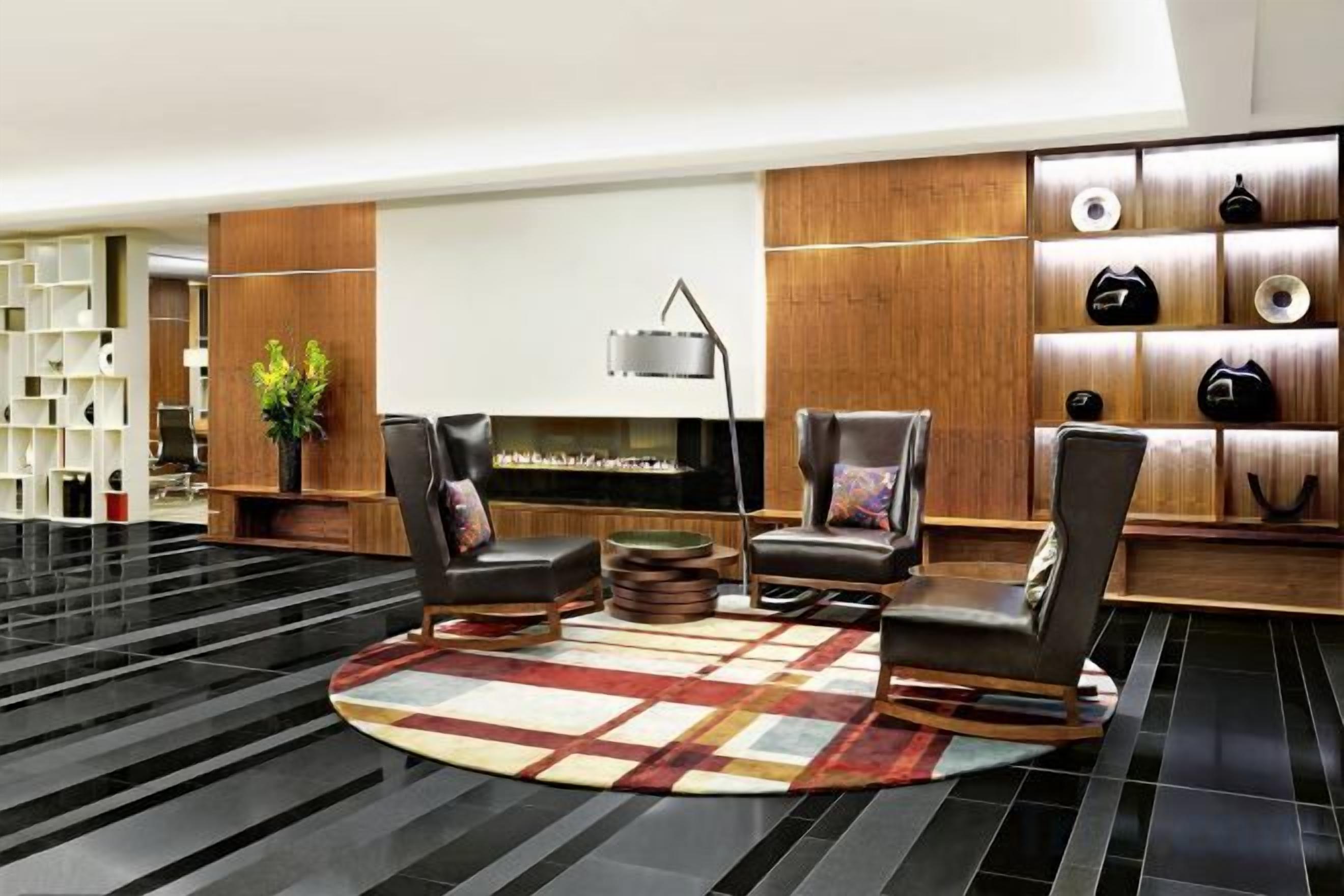 A modern lobby with a fireplace, leather chairs, a coffee table, and a shoe display.