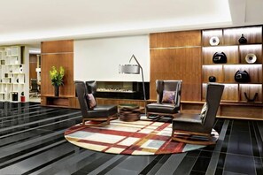 A modern lobby with a fireplace, leather chairs, a coffee table, and a shoe display. - Sheraton Grand Hotel & Spa (Edinburgh)