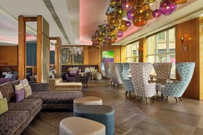 A spacious lobby with a modern design, featuring a seating area with sofas and armchairs, a reception desk, and a decorative ceiling with spherical ornaments. - Sheraton Grand Hotel & Spa (Edinburgh)