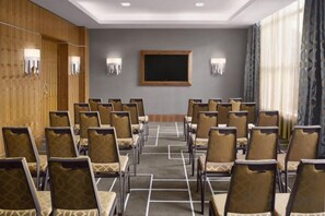 A conference room with rows of chairs, a blackboard, and wall-mounted lights. - Sheraton Grand Hotel & Spa (Edinburgh)