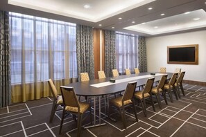 A conference room with a long table, chairs, a projector screen, and large windows with curtains. - Sheraton Grand Hotel & Spa (Edinburgh)