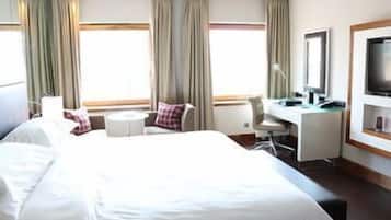 A hotel room with a large bed, a desk, a chair, a TV, and curtains.