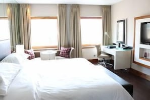 A hotel room with a large bed, a desk, a chair, a TV, and curtains. - Sheraton Grand Hotel & Spa, Edinburgh (Edinburgh)