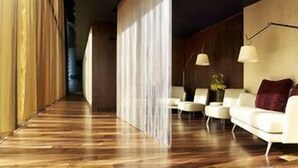 A modern interior with a wooden floor, white sofas, a lamp, and a curtain. - Sheraton Grand Hotel & Spa, Edinburgh (Edinburgh)