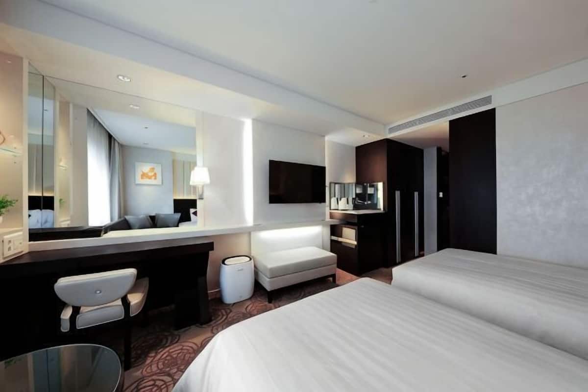 Une chambre d’hôtel avec un lit, un bureau, une chaise, une télévision et un grand miroir.