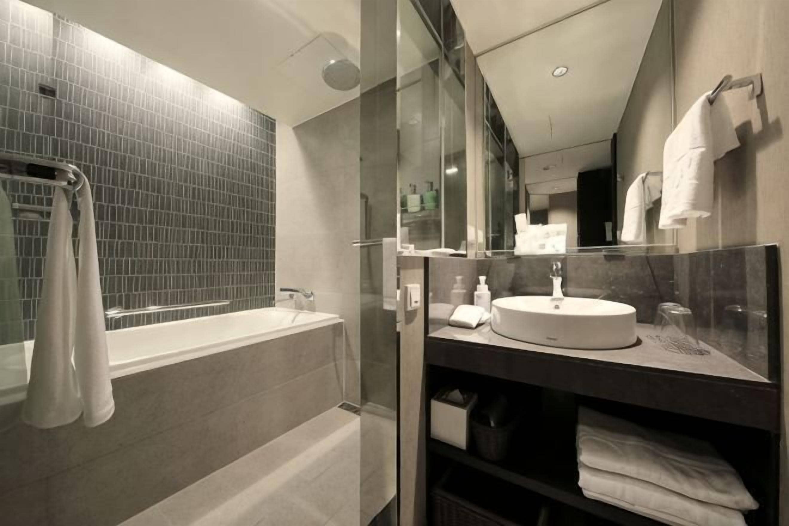 Ein modernes Badezimmer mit einer gläsernen Duschkabine, einer freistehenden Badewanne und einem Waschtisch mit Spüle und Spiegel.