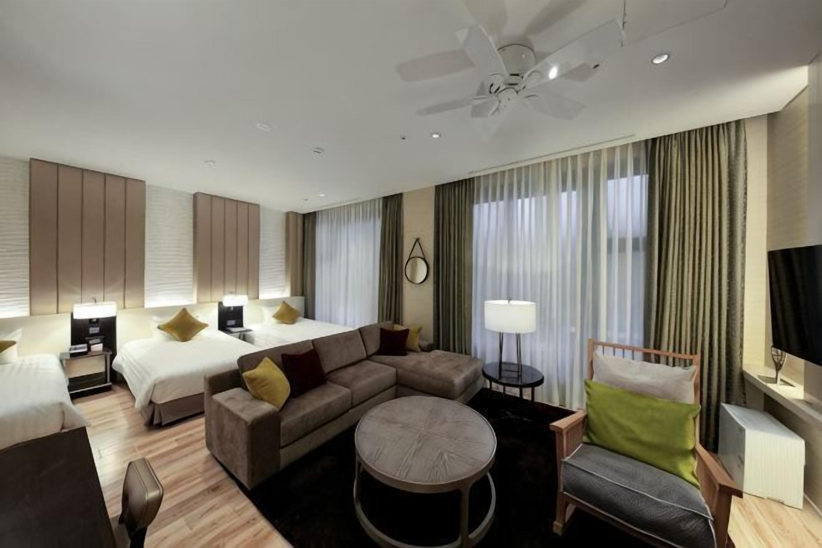 Ein Hotelzimmer mit Bett, Sofa, Sessel und rundem Tisch.