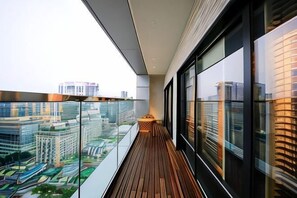 Een balkon met uitzicht op de stad, een houten vloer en grote ramen.