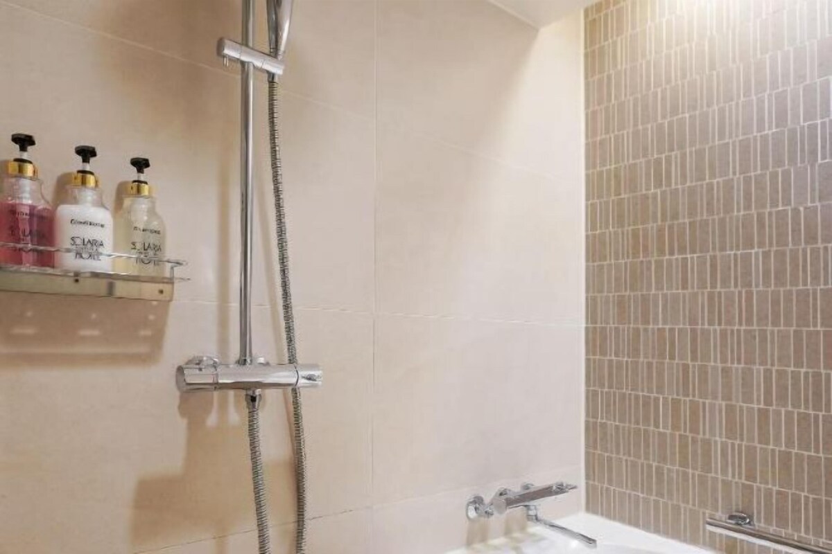 A bathroom with a shower, a bathtub, and a shelf with toiletries.
