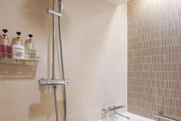 A bathroom with a shower, a bathtub, and a shelf with toiletries. - Solaria Nishitetsu Hotel Seoul Myeongdong (Seoul)