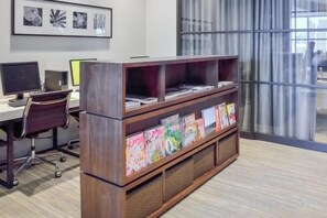 Un espacio de trabajo con un escritorio de madera, monitores de computadora y una estantería con libros de colores.