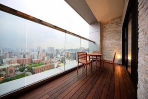 A balcony with a wooden floor, a table, and chairs.