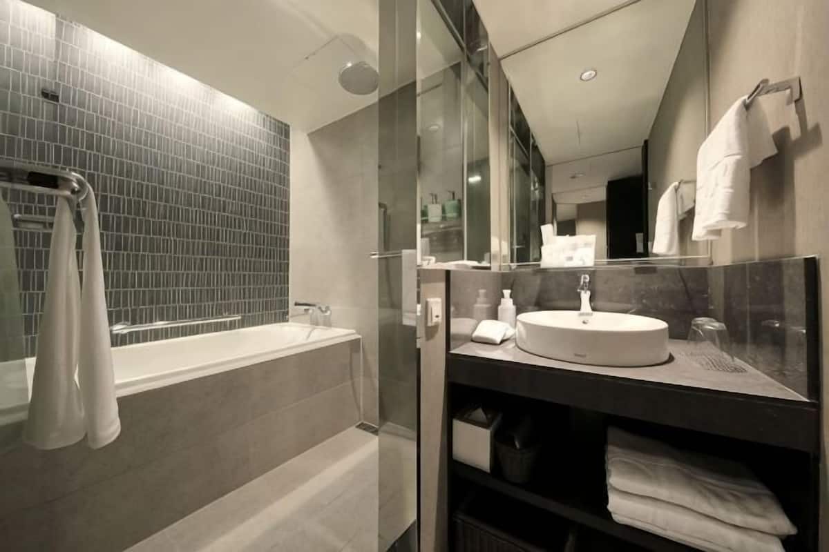A modern bathroom with a glass-enclosed shower, a white sink, and a large mirror.