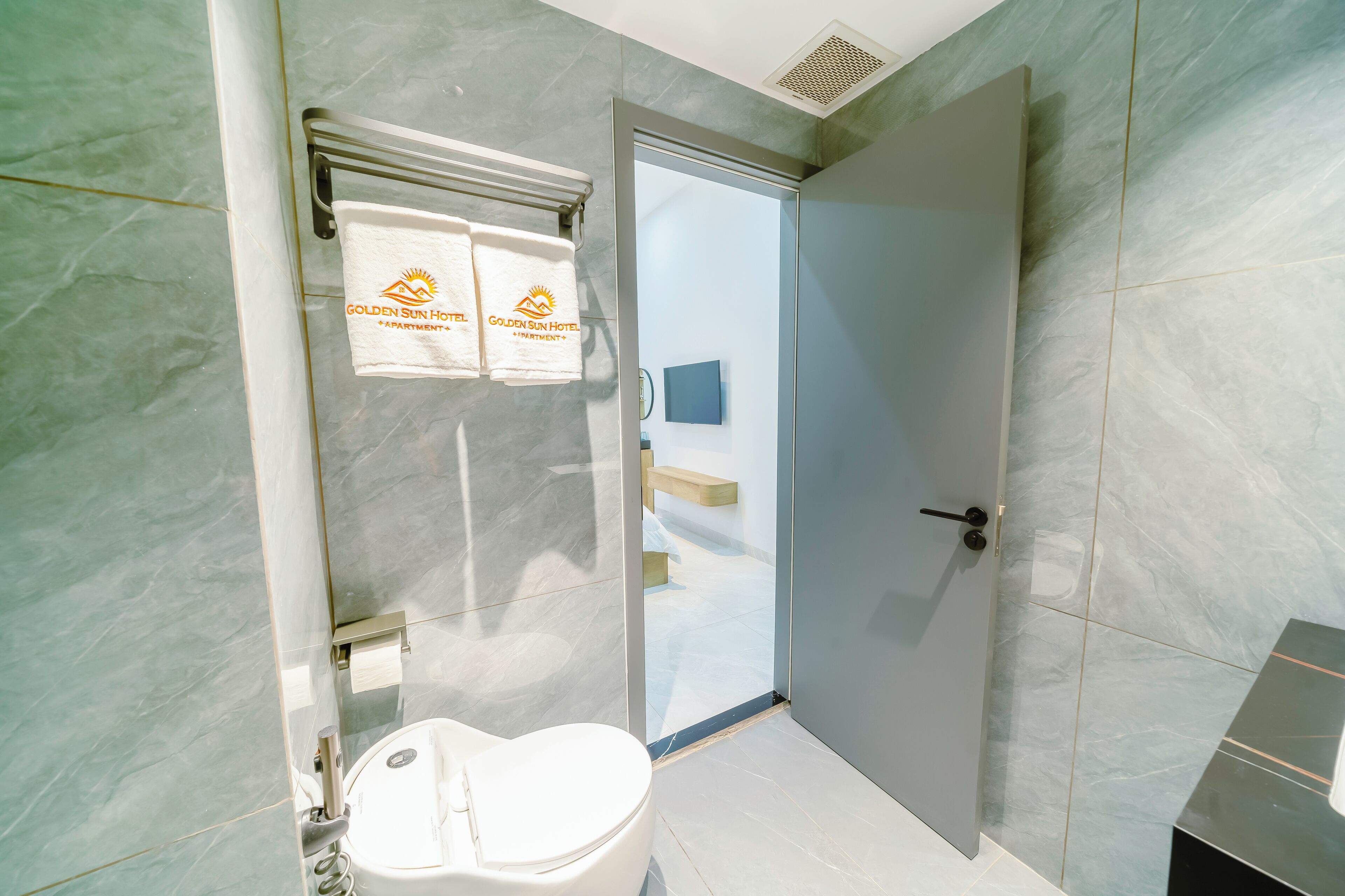 A modern bathroom with a toilet, a glass shower enclosure, and a towel rack with two towels.