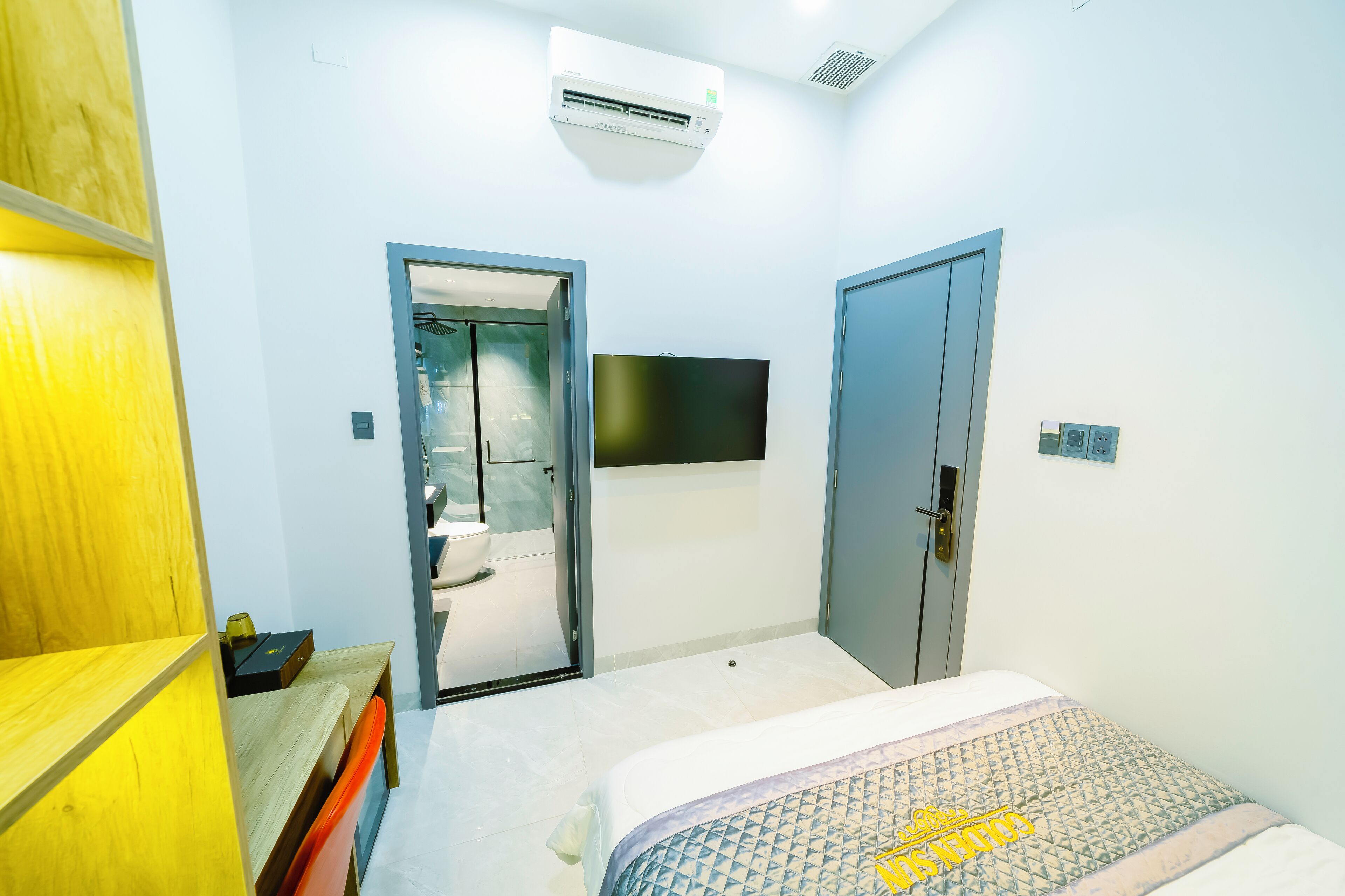 Quarto com cama, televisão na parede e ar condicionado.