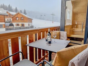 A wooden deck with a table and chairs, a bottle of wine, and a glass on the table.