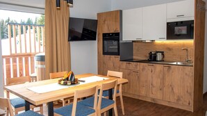 A modern kitchen with wooden cabinets, a built-in oven, and a flat-screen TV. - Exquisite flat with sauna on the piste (Weißpriach)