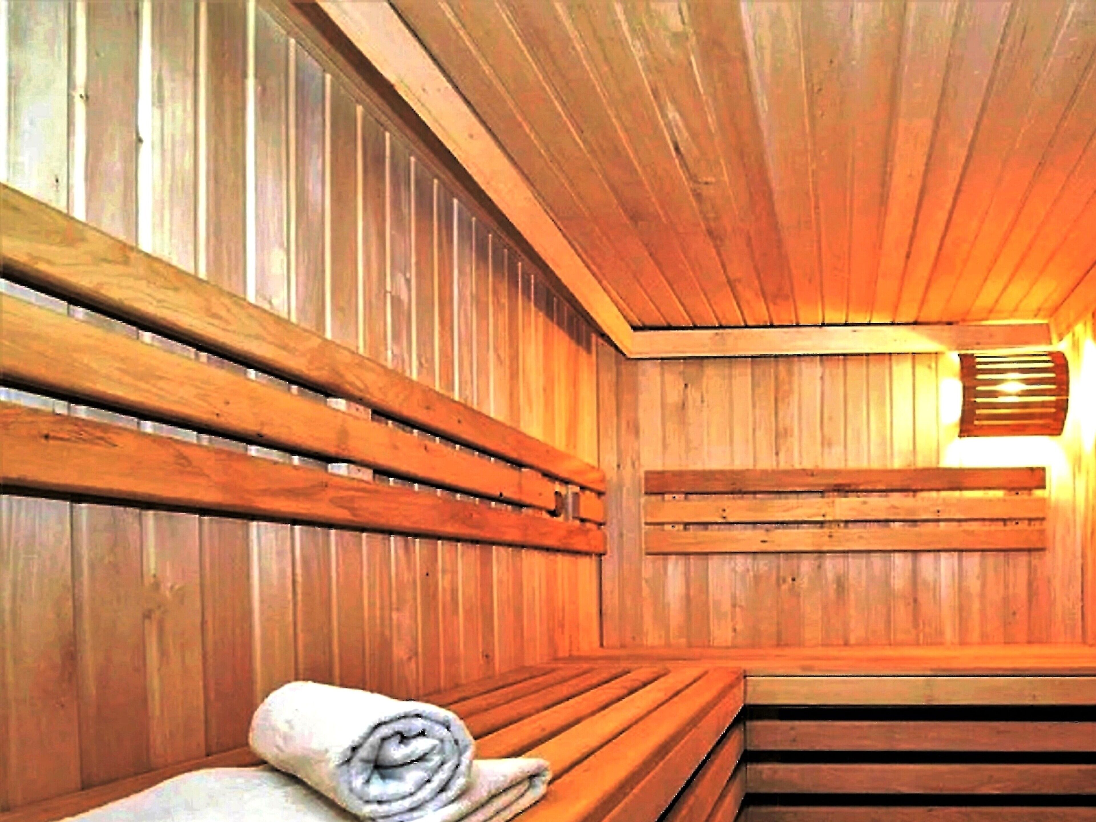 A wooden sauna with benches and a towel on the floor.