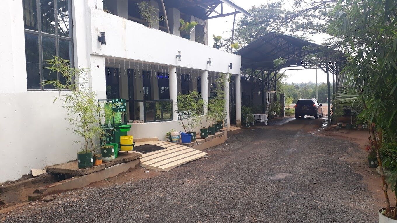 A building with a covered entrance, potted plants, and a gravel driveway.