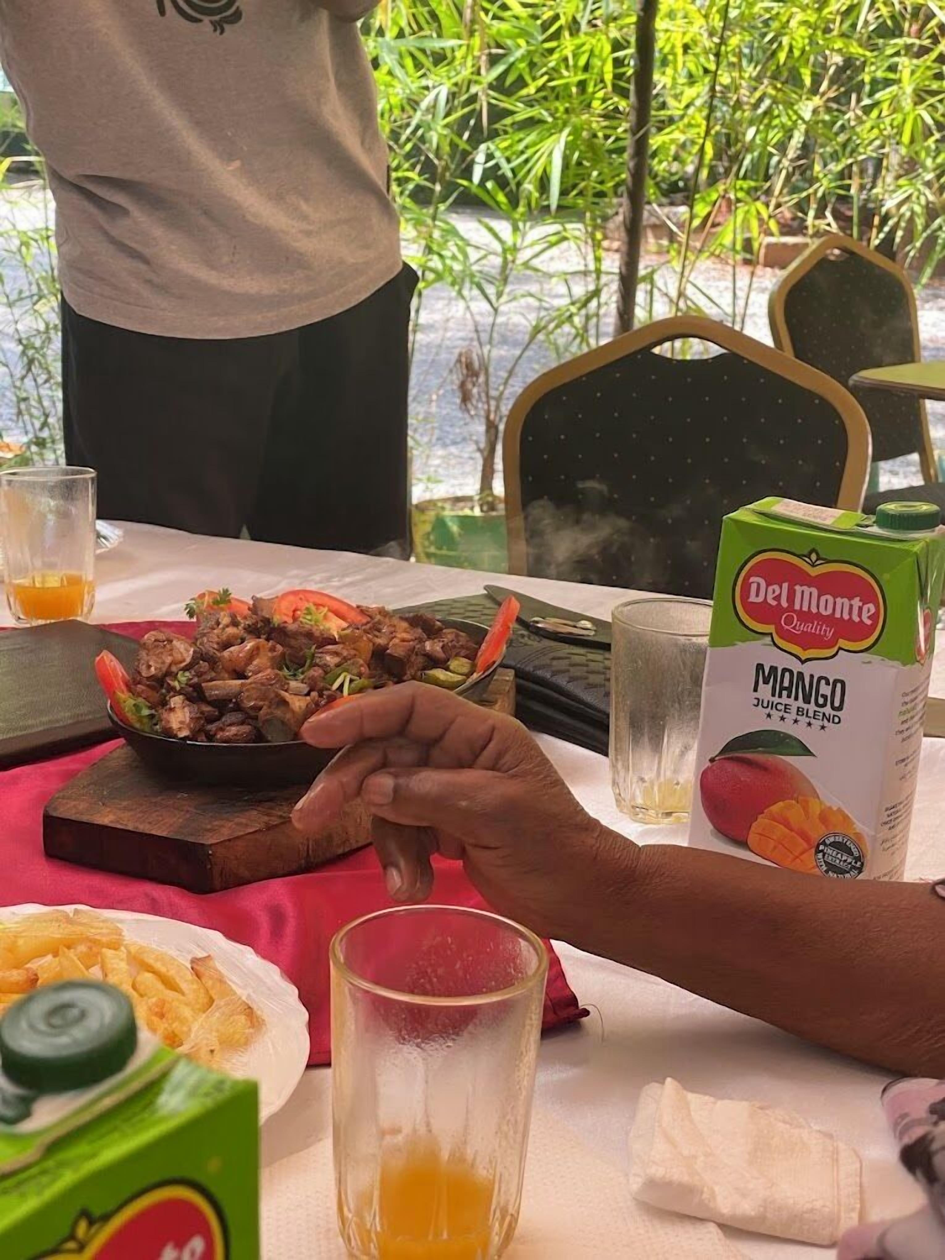 A dining table with a meal, a glass of juice, and a juice box.