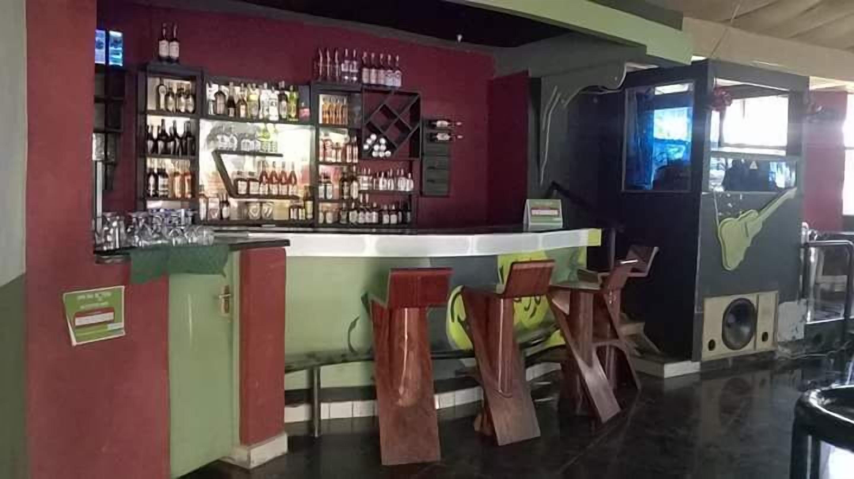 A bar area with a counter, stools, and shelves of bottles.
