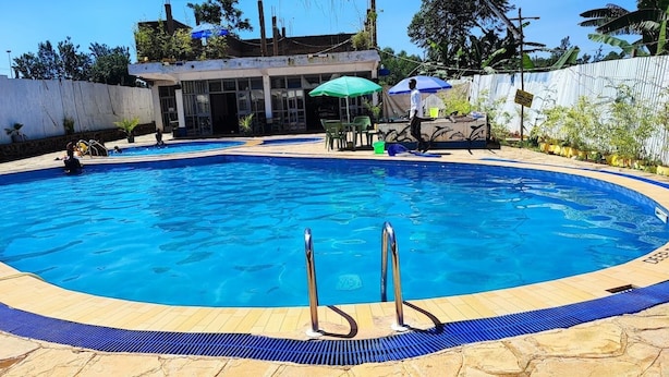 Una piscina con acqua cristallina, circondata da un solarium in pietra e un muro bianco.