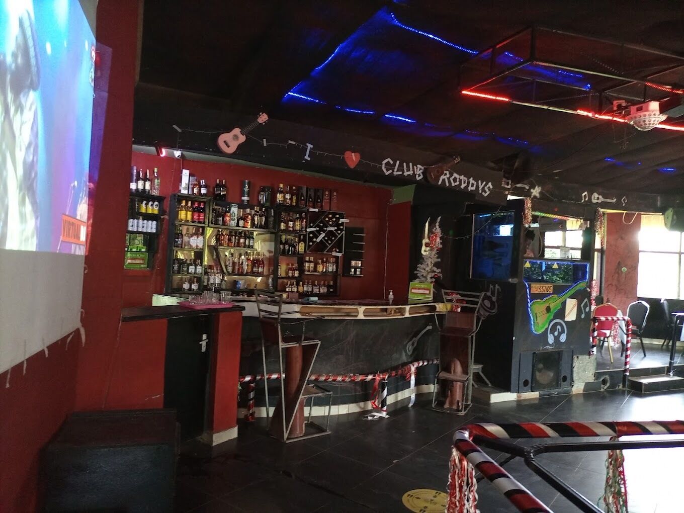 Zona de bar con barra, estanterías llenas de botellas y un cartel que dice 'CLUB AOPPS'.