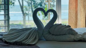 A room with a bed, a window with a view of the ocean, and a towel arranged in the shape of a heart. - Andromeda Gazirtek (Cox's Bazar)