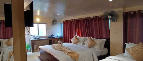 A hotel room with two beds, a desk, and a TV.