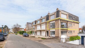 A two-story residential building with a garage, a driveway, and a street view. - Renovated flat centrally located (Koksijde)