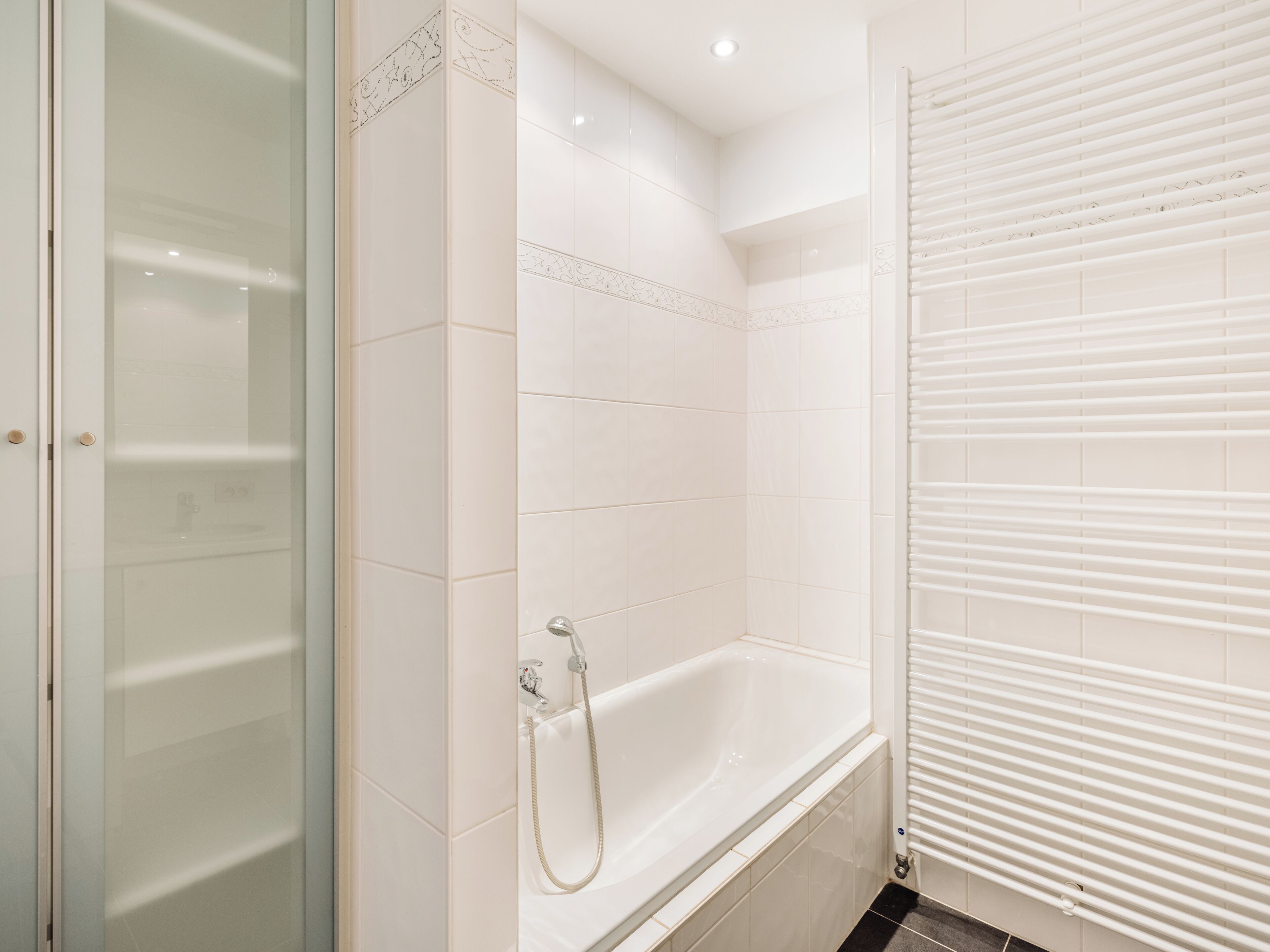 Een badkamer met een bad, douche en een douchecabine met glazen wanden.