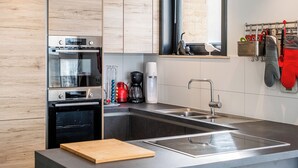 A modern kitchen with stainless steel appliances, a wooden countertop, and a built-in sink. - Beautifully renovated flat with sea views (Koksijde)