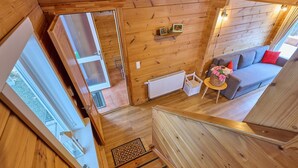 Interior de madera con una escalera que lleva a una sala de estar con sofá y una mesita con flores.