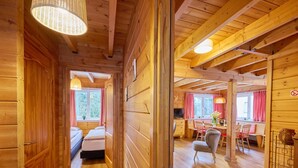 Interior de una cabaña de madera con un pasillo que conduce a un dormitorio y un comedor.