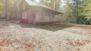 Eine rustikale Holzhütte mit einer Holzterrasse und einem Metalldach, umgeben von einem Wald.