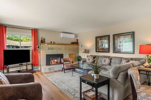 A living room with a fireplace, a sofa set, a television, and a coffee table. - Near Leavenworth Riverfront 6BR + Hot Tub Retreat (Peshastin)