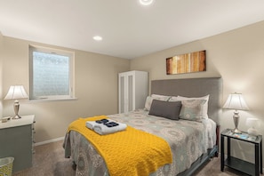 A bedroom with a bed, a window, a wardrobe, and a bedside table.