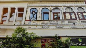 A multi-story building with traditional architectural features, including arched windows and decorative patterns. - Neev Haveli (Udaipur)