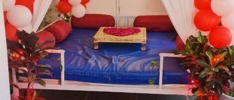 A room with a bed, a neon 'Happy Birthday' sign, and red and white balloons.