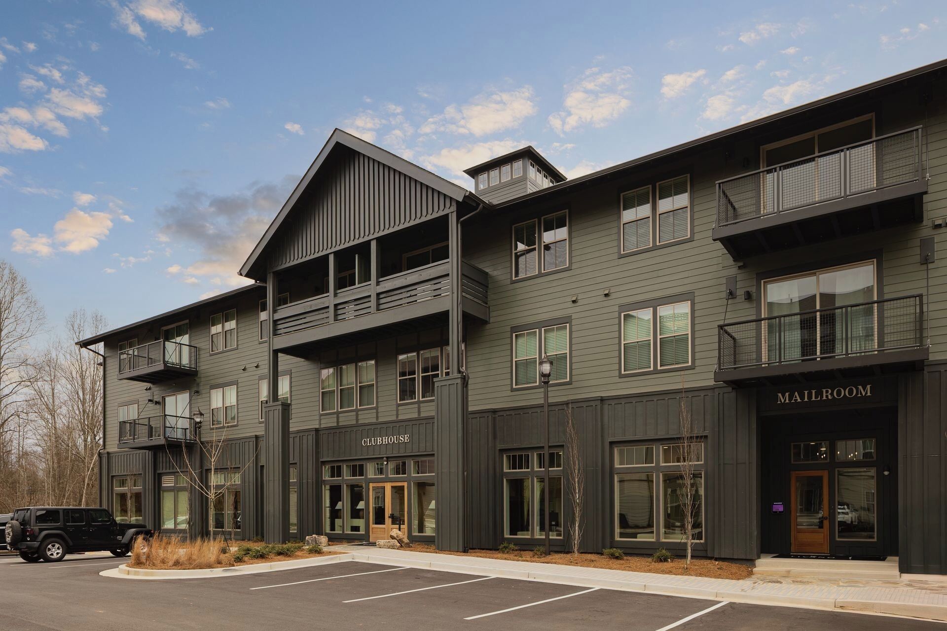 A modern building with a 'CLUBHOUSE' sign, multiple balconies, and a 'MAILROOM' sign.