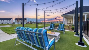 A patio with outdoor seating, a fire pit, and string lights. - Landing Apartments - Lebanon, IN (Lebanon)