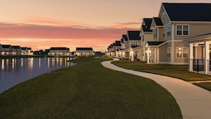 A row of single-family homes with a well-maintained lawn and a curved pathway leading to a body of water. - Landing Apartments - Lebanon, IN (Lebanon)