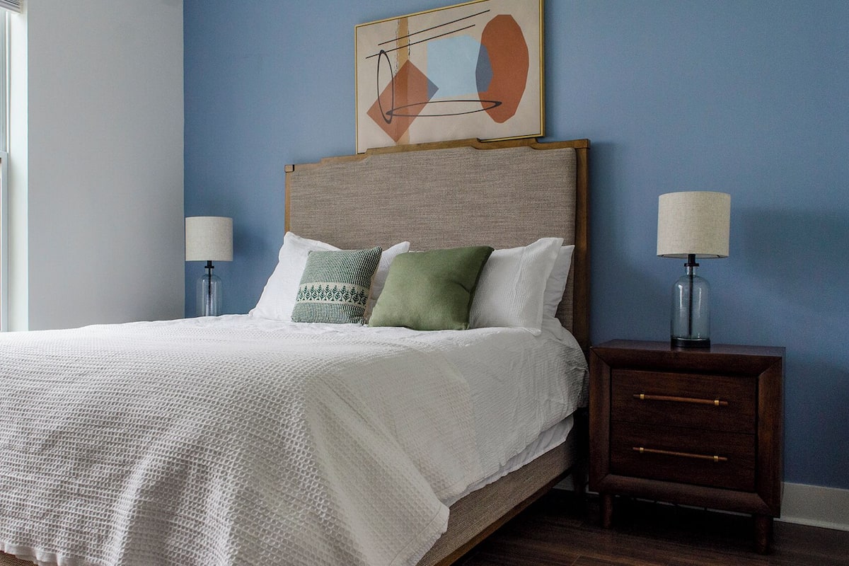 A bedroom with a bed, two bedside tables, and a window.