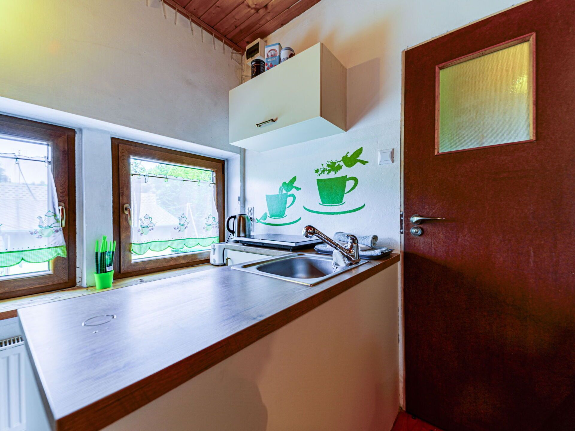 Eine Küche mit Holzarbeitsplatte, Spüle, Fenster mit Blick und einer Tür mit satiniertem Glas.
