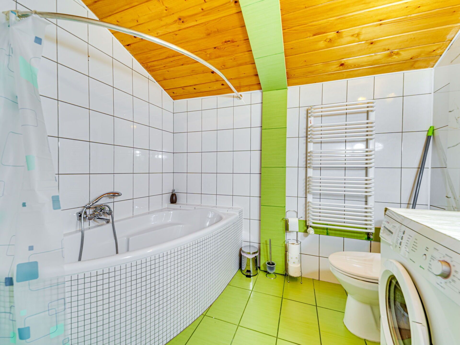 Casa de banho moderna com banheira, sanita e máquina de lavar roupa.