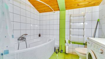 Casa de banho moderna com banheira, sanita e máquina de lavar roupa.