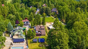 Zona residencial con casas rodeadas de un bosque denso, con paneles solares y una piscina.